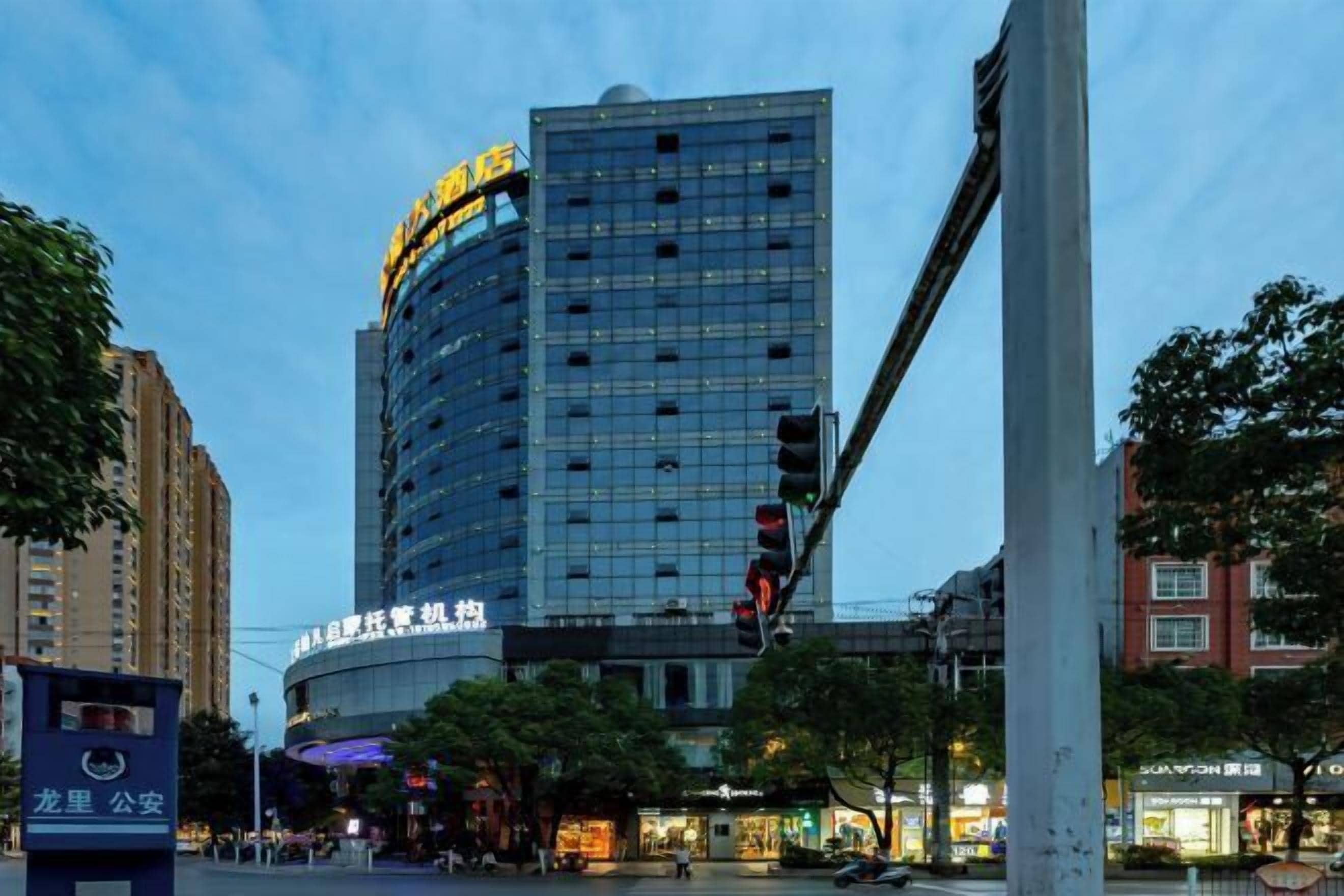 A modern high-rise building with a curved facade, featuring multiple floors and a prominent sign at the top.