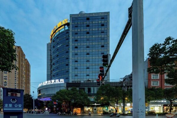 A modern high-rise building with a curved facade, featuring multiple floors and a prominent sign at the top. - Jilong Hotel (Longli County Traditional Chinese Medicine Hospital) (Longli)
