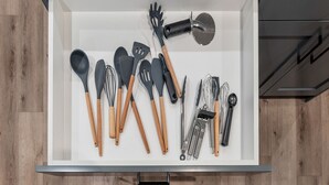 Un tiroir de cuisine contenant divers ustensiles, notamment des spatules, des pinces et une râpe.