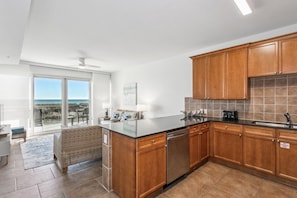 A modern kitchen with wooden cabinets, a black countertop, and a built-in dishwasher.