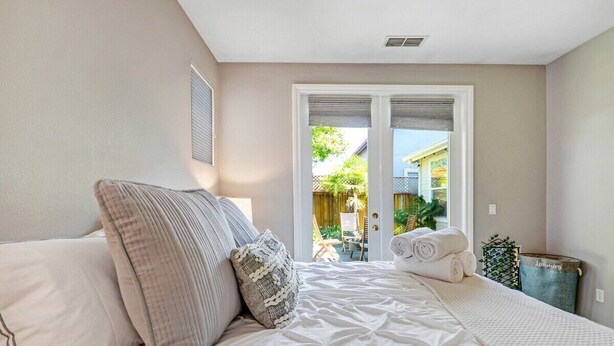 Een slaapkamer met een bed, kussens, een raam en uitzicht op buiten.