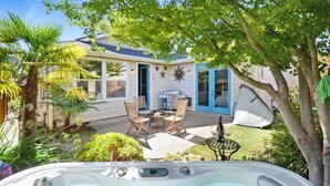 Een achtertuin met een hottub, terrasmeubels, een barbecue en een overdekte patio.