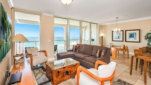 A spacious living room with a large sofa, a coffee table, and a dining area with wooden furniture.