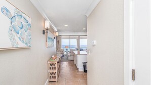 Un pasillo con vistas a una sala de estar, un cuadro en la pared y una pequeña mesa con objetos.