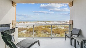Un balcón con vista a una playa y dunas.