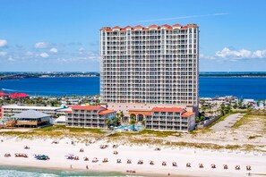 A high-rise hotel with multiple balconies, a beachside location, and a view of the ocean.