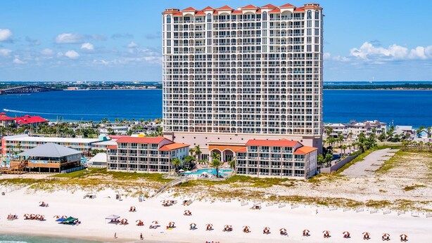 Un hotel moderno de altura con varios balcones, ubicación frente a la playa y vistas al océano.