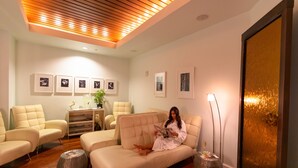 Una sala de estar moderna con un sofá, sillones, techo de madera y cuadros enmarcados en la pared.