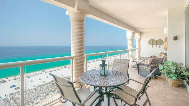 A balcony with a view of the beach, a round table with chairs, wicker furniture, and a potted plant. - Dly Beach Chairs! -Beach Club 3B Gulf Front @ Pensacola Bch (Pensacola Beach)