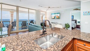 A kitchen with a granite countertop, stainless steel sink, and a view of the ocean through large sliding glass doors. - Dly Beach Chairs! -Beach Club 3B Gulf Front @ Pensacola Bch (Pensacola Beach)