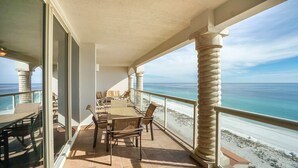 Ein überdachter Außenbereich mit Tisch und Stühlen mit Blick auf einen Strand.