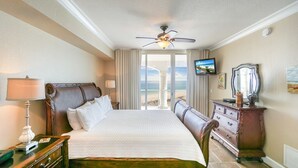 Ein Hotelzimmer mit Bett, Schminktisch, Fernseher und Blick auf den Strand.
