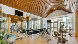 Uma academia com equipamentos de exercício, espelhos e grandes janelas.
