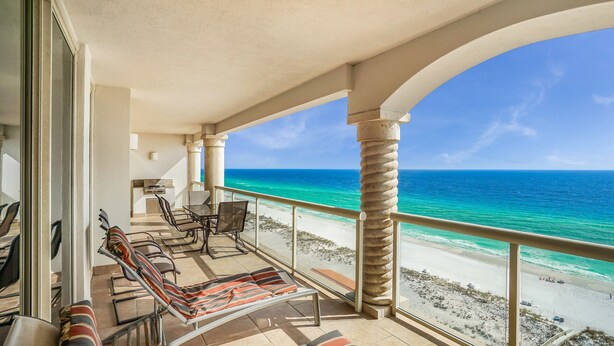 Uma varanda com vista para o oceano, equipada com cadeiras e uma mesa.