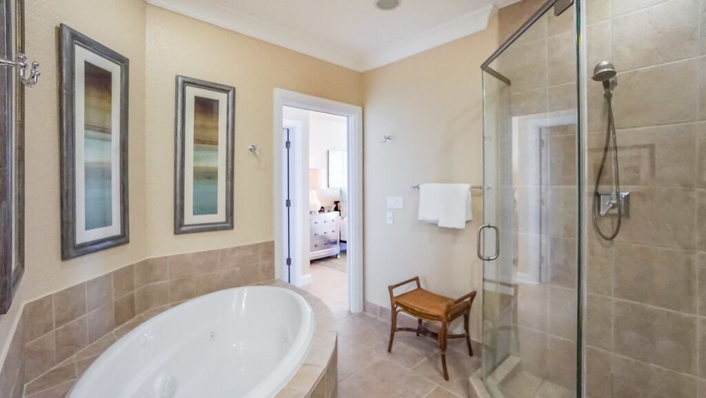 Un baño con bañera, cabina de ducha de vidrio y una silla de madera.
