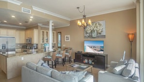 A spacious living area with a kitchen, dining area, and a large flat-screen TV.