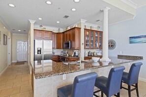 Una cocina moderna con encimeras de granito, armarios de madera y una isla central con taburetes de bar.