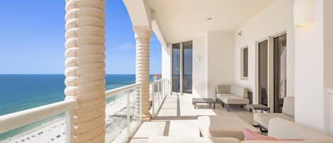 Enjoy the ocean view from this spacious balcony with a sofa and armchairs.