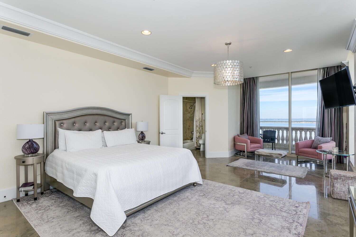 Un dormitorio amplio con una cama grande, una zona de estar con televisor y vistas al mar.