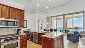 A modern kitchen with granite countertops, stainless steel appliances, and wooden cabinets. - BC-2003 3B Beach Club Gulf Front /Daily Beach Chairs! (Pensacola Beach)