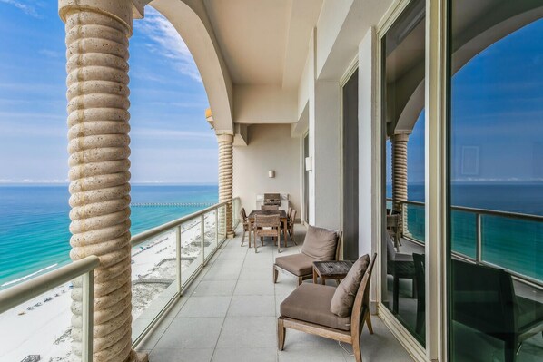 Enjoy the ocean view from this balcony with a table and chairs.