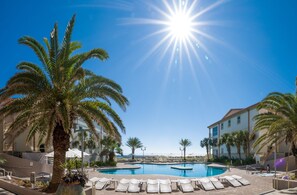 Relax by the pool surrounded by palm trees and resort buildings.