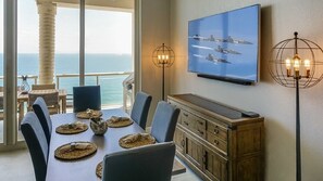 Enjoy meals with a view of the ocean from this dining area, featuring a large table for six and a unique floor lamp.