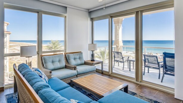 Ein geräumiges Wohnzimmer mit großem Fenster und Meerblick, ausgestattet mit einer Couch, Sesseln und einem Couchtisch.