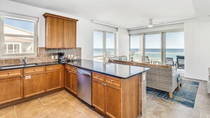Eine moderne Küche mit Holzschränken, einer schwarzen Arbeitsplatte und Meerblick.