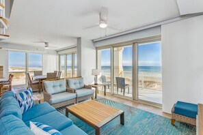 Relax in this beach-facing living area with a sofa, coffee table, and wicker furniture.