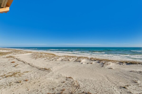 Una playa con cielo despejado y mar tranquilo.