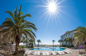 Relax by the pool surrounded by palm trees and ocean views.