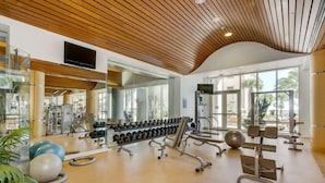 A gym with exercise equipment, mirrors, and large windows.