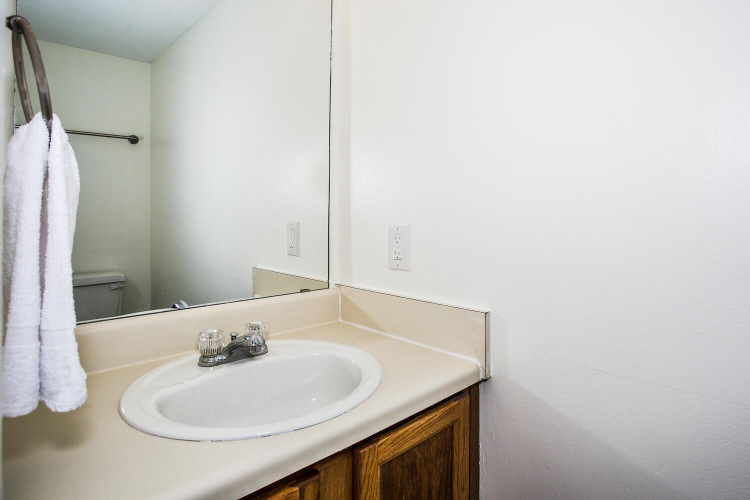 A bathroom with a white sink, a mirror, and a towel hanging on a rack.