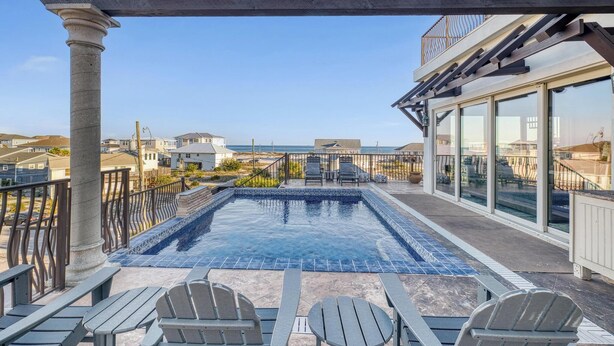 A rooftop pool with a pergola, outdoor seating, and a view of the ocean. - Roof Top Pool at the High Life - 1 Block from the Beach! (Pensacola Beach)