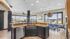 A kitchen with a large island, dark cabinetry, and a view of the ocean. - Roof Top Pool at the High Life - 1 Block from the Beach! (Pensacola Beach)