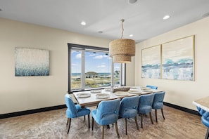 A dining area with a large table, blue chairs, and a hanging light fixture.