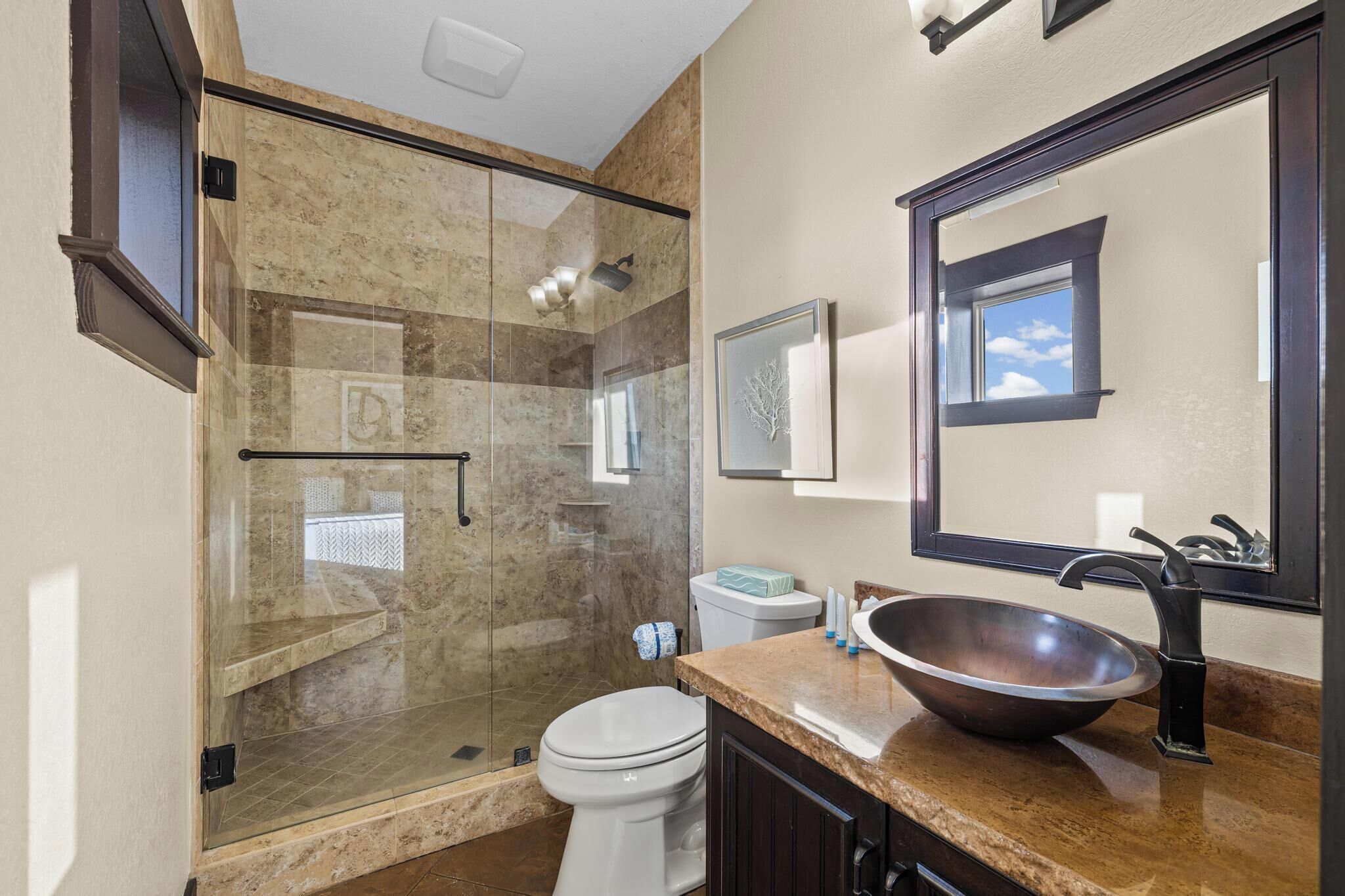 Une salle de bain moderne avec une douche à parois de verre, des toilettes blanches, un grand miroir et un lavabo sur colonne.