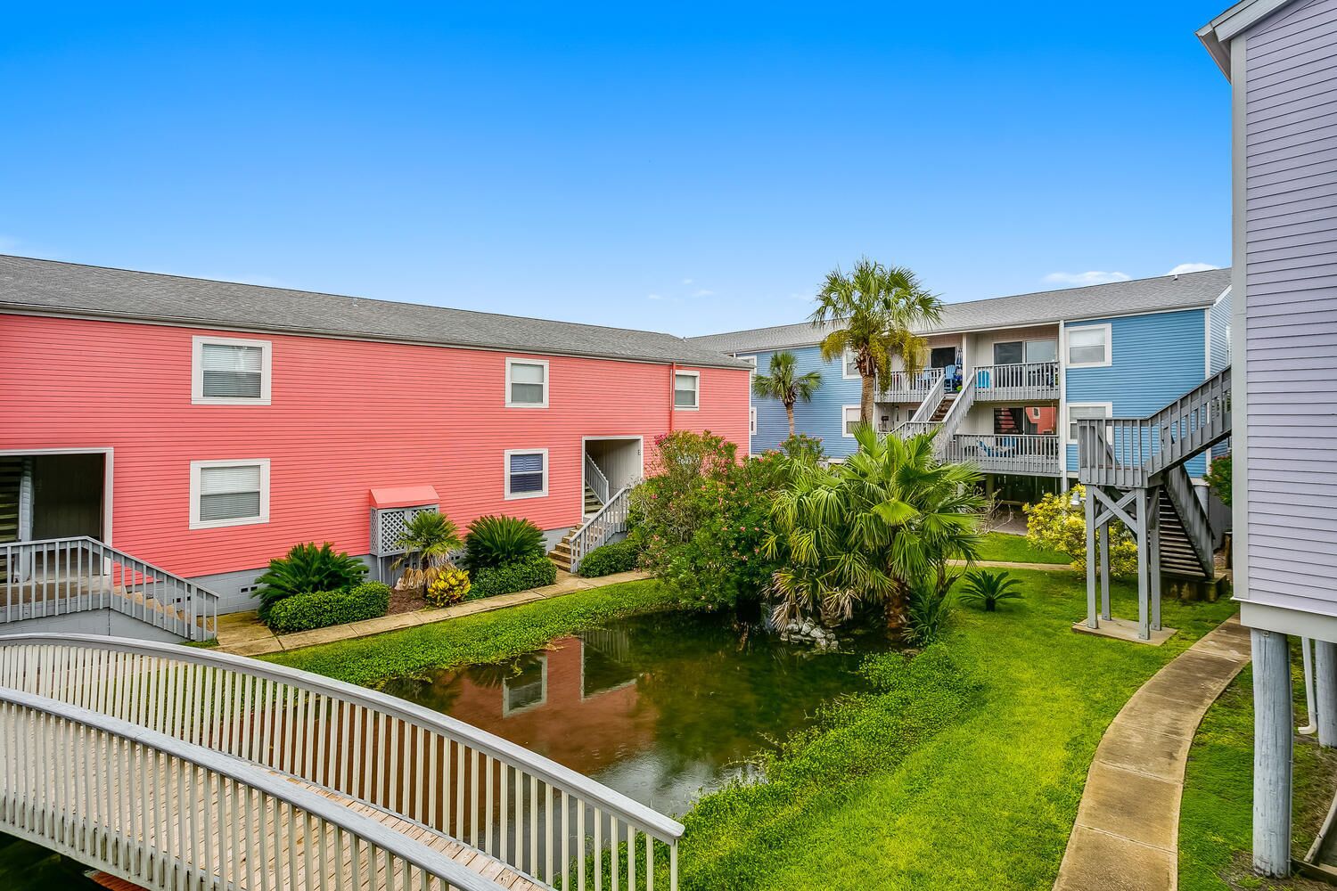 A courtyard with a small pond, surrounded by multi-story buildings with balconies and staircases.
