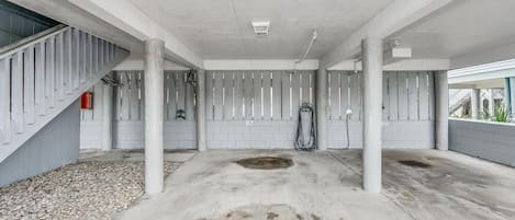 A spacious indoor area with concrete pillars, a staircase on the left, and a hose reel on the right.