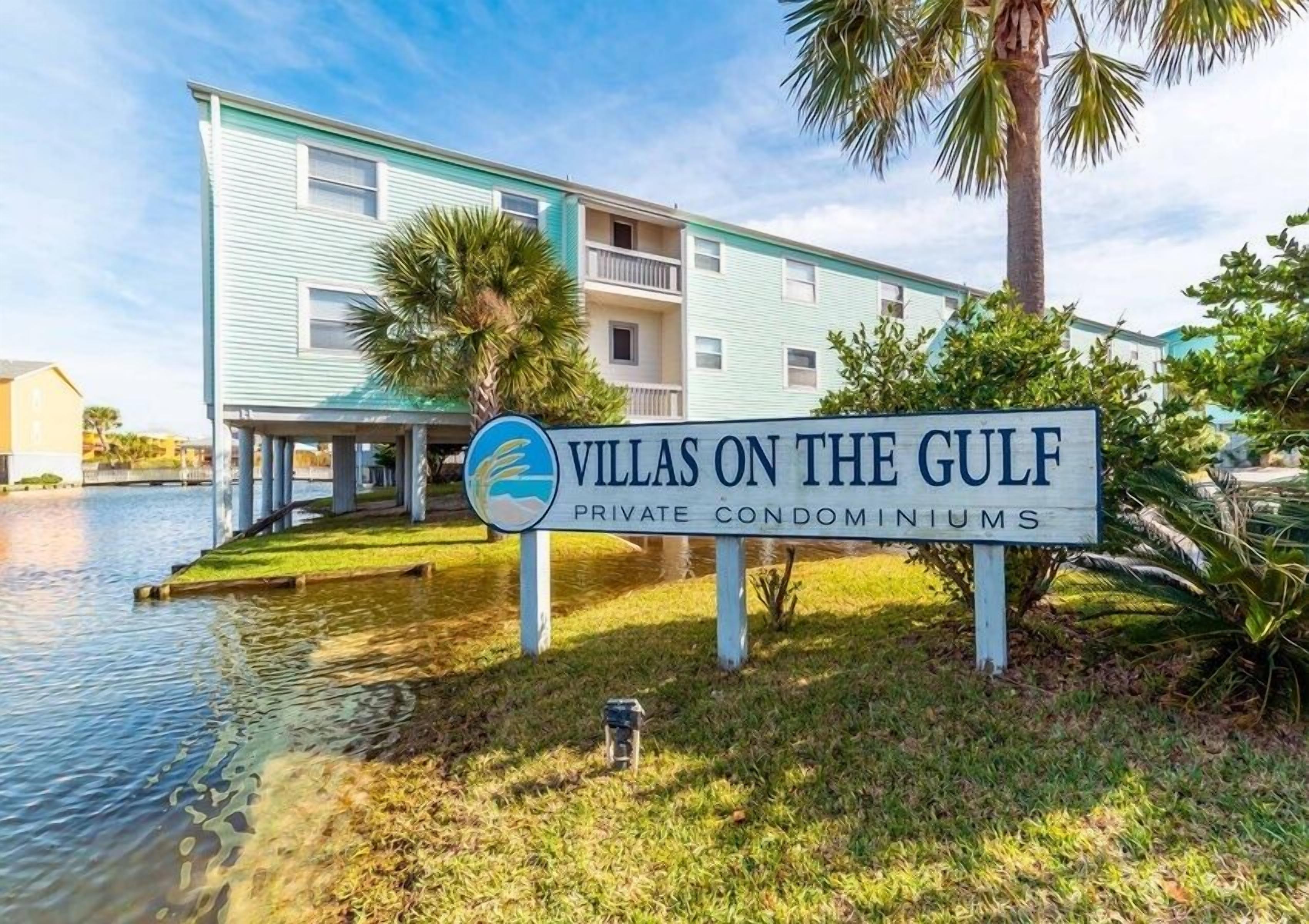 A sign for 'Villas on the Gulf' private condominiums with a water body in the foreground.
