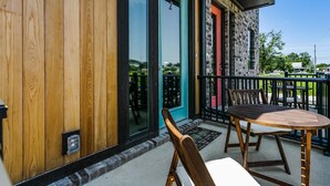Een houten gevel, een glazen deur, een balkon met een tafel en stoelen, en een bakstenen gebouw met een rode deur.