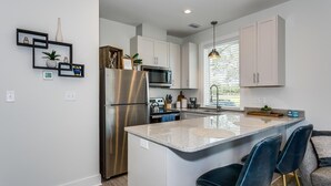 A modern kitchen with a central island, stainless steel appliances, and a view of the outdoors. - Bushwacker - European flare in downtown Pensacola (Pensacola)