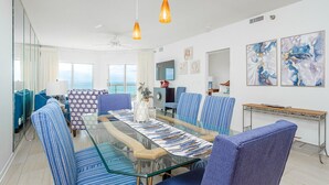 Un comedor moderno con una mesa de vidrio y sillas a rayas azules, con vistas a un paisaje pintoresco.