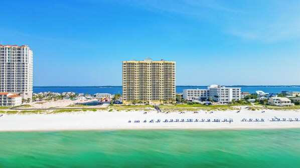 A coastal hotel with multiple high-rise buildings, a beach, and clear blue skies. - 2B Emerald Isle - Stunning Gulf Front Views! (Pensacola Beach)