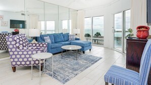 Una sala de estar moderna con un sofá azul, un sillón estampado y una mesa de centro redonda.