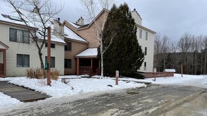 A residential area with houses, a wooden deck, and a snow-covered ground. - Cozy 2 BR Condo With Spectacular View of Mount Snow! (Dover)