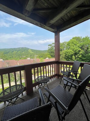 Relax in this serene outdoor seating area with a view of the surrounding green landscape.