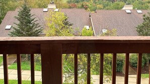 A wooden deck with a metal table and chairs, overlooking a residential area with houses and a hilly landscape. - Cozy 2 BR Condo With Spectacular View of Mount Snow! (Dover)
