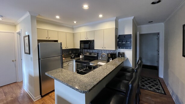 A modern kitchen with granite countertops, stainless steel appliances, and a bar area. - Cozy 2 BR Condo With Spectacular View of Mount Snow! (Dover)